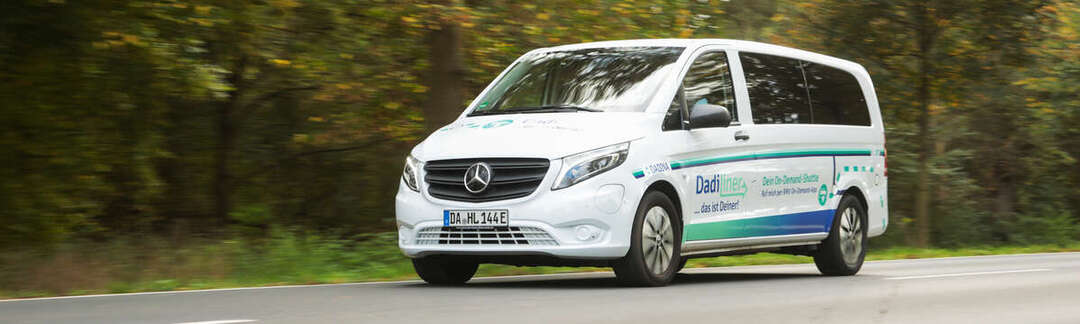 Ein weißes großes Auto fährt auf einer Straße im Grünen