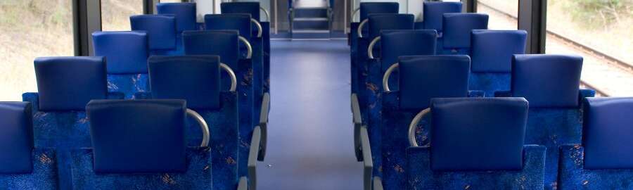 Inside of a train wagon with empty blue seats