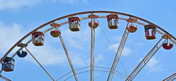 Gondeln eines Riesenrads vor blauem Himmel