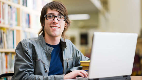 Student smiling in the camera with laptop in the library