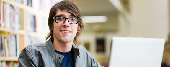 Student smiling in the camera with laptop in the library