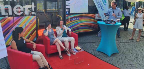 Drei Frauen sitzen auf dem roten Sofa vor dem Mobilitätsbus.
