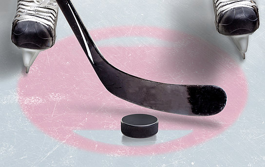 Detailaufnahme eines Eishockeyspielers mit Schlittschuhen, Schläger und Puck.