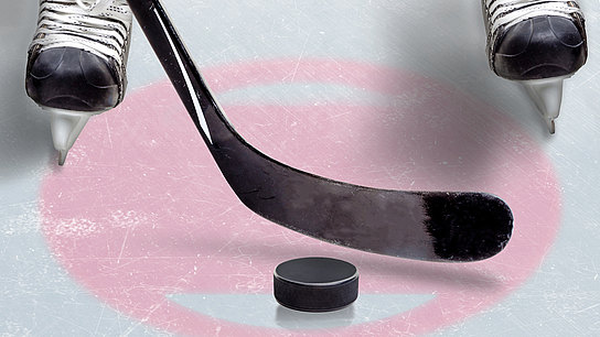 Detailaufnahme eines Eishockeyspielers mit Schlittschuhen, Schläger und Puck.