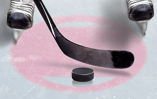 Detailaufnahme eines Eishockeyspielers mit Schlittschuhen, Schläger und Puck.