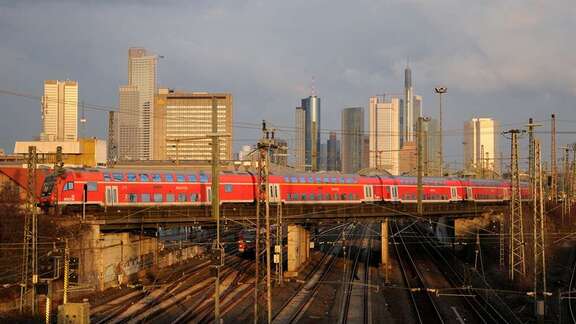 S-Bahn fährt über Brücke vor Frankfurter Skyline