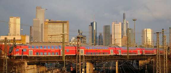 S-Bahn fährt über Brücke vor Frankfurter Skyline