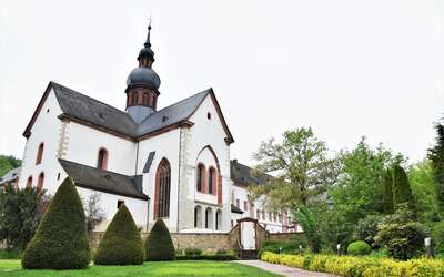 Historisches Gebäude mit Kirchturm in einer Parkanlage