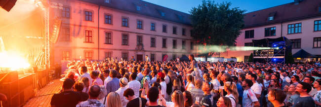 Konzert mit Bühne und Menschen in einem Innenhof eines historischen Gebäudes