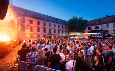 Konzert mit Bühne und Menschen in einem Innenhof eines historischen Gebäudes