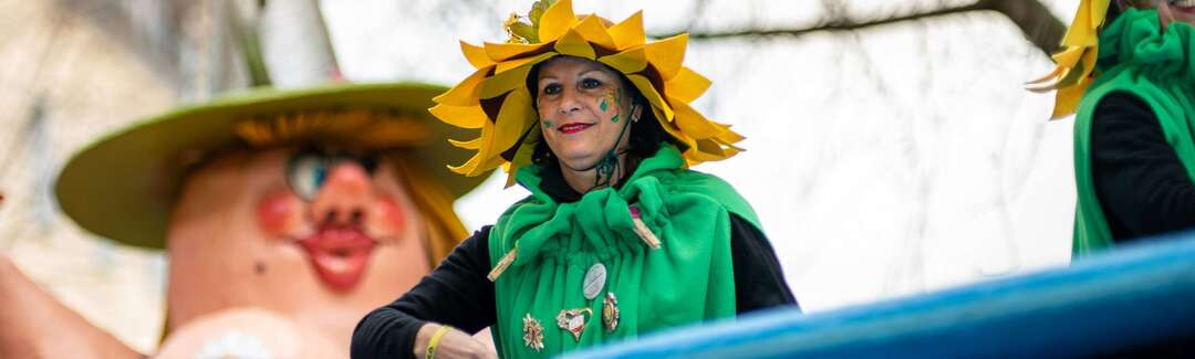 Kostümierte Frau mit Sonnenhut au einem Wagen