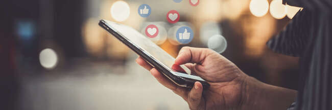 Stockfoto mit einem Handy, aus dem Likes und Herzen aufsteigen