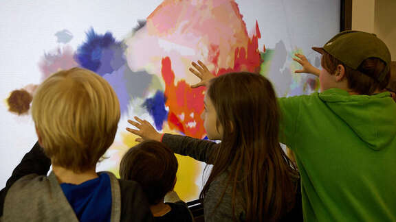 Kinder betasten ein modernes Gemälde.