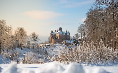Großes Schloss mit Schnee bedeckt vor blauem Himmel 