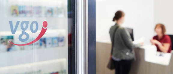 Glastür mit vgo-Schriftzug, im Hintergrund Kundengespräch