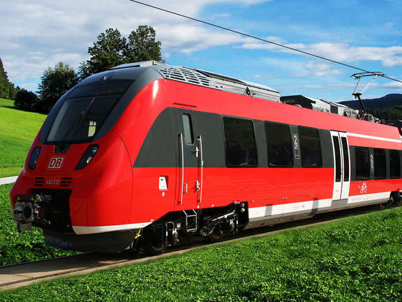 Vergrößerte Ansicht: Roter Zug fährt durch grüne Landschaft
