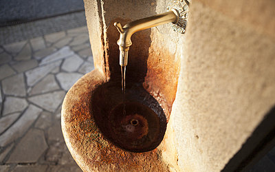 Vergrößerte Ansicht: Kleiner Trinkbrunnen aus Stein mit goldenem Wasserhahn