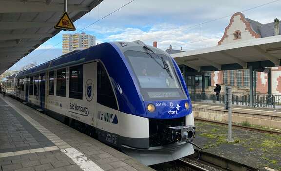 Blauweißer Zug steht auf einem Gleis im Bahnhof