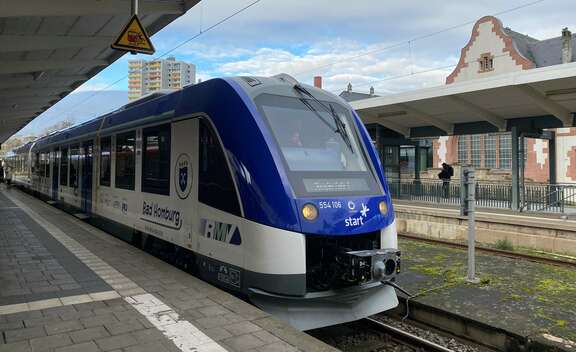 Blauweißer Zug steht auf einem Gleis im Bahnhof