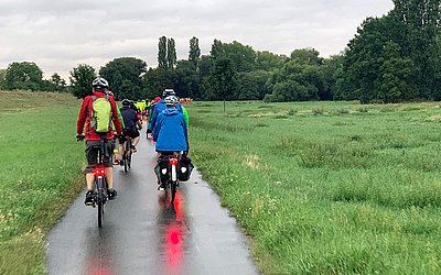 Gruppe von Menschen die auf einem Feldweg Fahrrad fahren