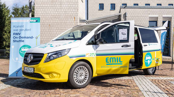 RMV-On-Demand-Shuttle in Taunusstein Großes Auto Mehrtürer gelb und Grün vor einem Gebäude