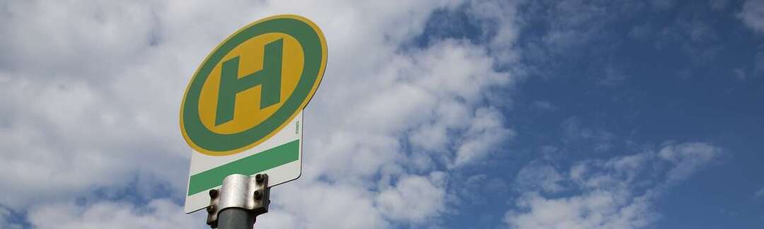 Nahaufnahme: Haltestellensymbol im Freien vor einem blauen Himmel