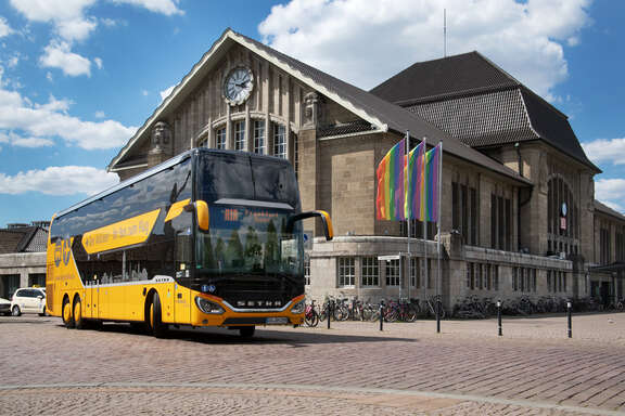 Airliner Ein orangefarbener Bus mit Aufschrift AirLiner steht vor einem Bahnhofsgebäude