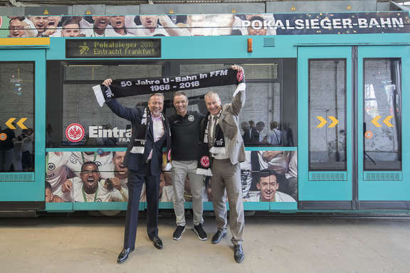 Pokalsieger-Straßenbahn Prof. Knut Ringat und zwei weitere Herren mit Eintracht-Schal vor einer Eintracht Straßenbahn