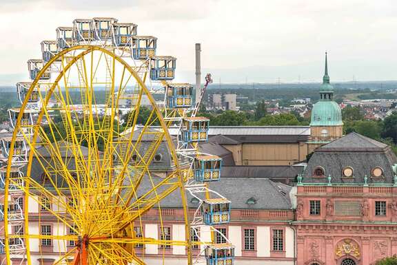 Ein großes gelbes Riesenrad vor dem Hintergrund historischer Gebäude in Darmstadt