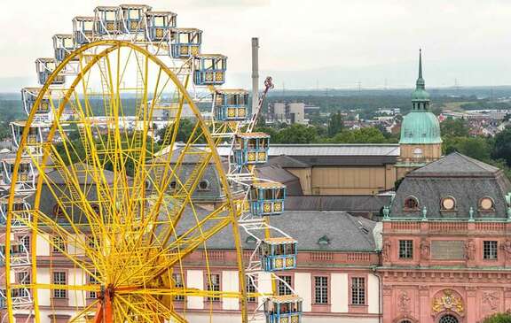 Ein großes gelbes Riesenrad vor dem Hintergrund historischer Gebäude in Darmstadt