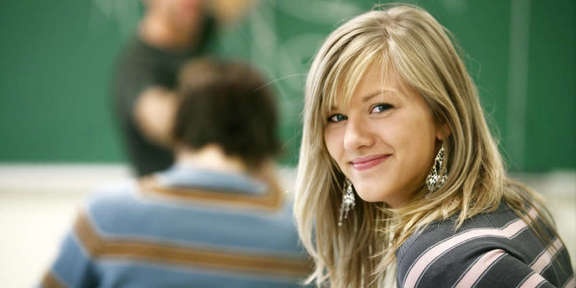 Schülerin im Klassenzimmer vor Tafel schaut hinter sich
