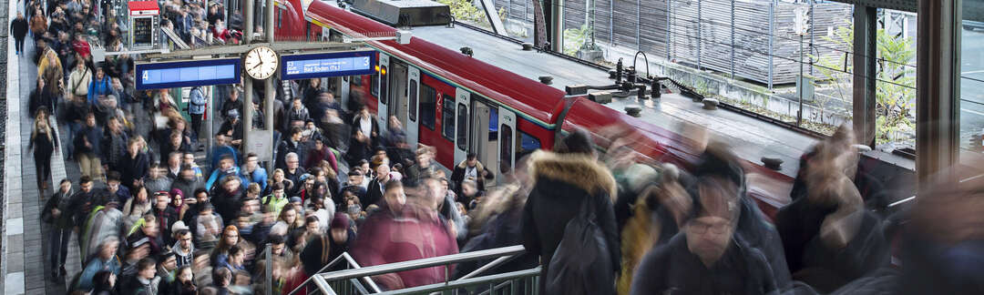 Viele Menschen kommen aus einer S-Bahn und überfüllen den Bahnsteig sowie die Bahnsteigtreppe.