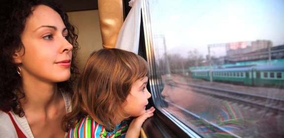 Frau und Kind auf dem Schoß schauen aus dem Zugfenster