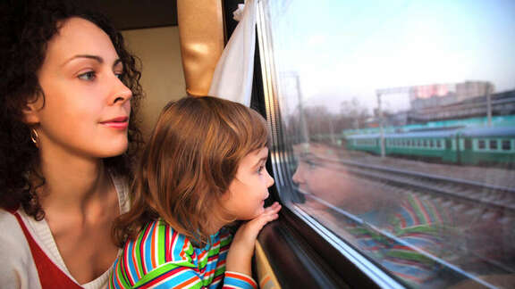 Young woman and a young girl are looking out of a train window