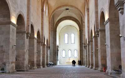 Kircheninnenraum mit gepflastertem Steinboden, Pfeilern und Bögen