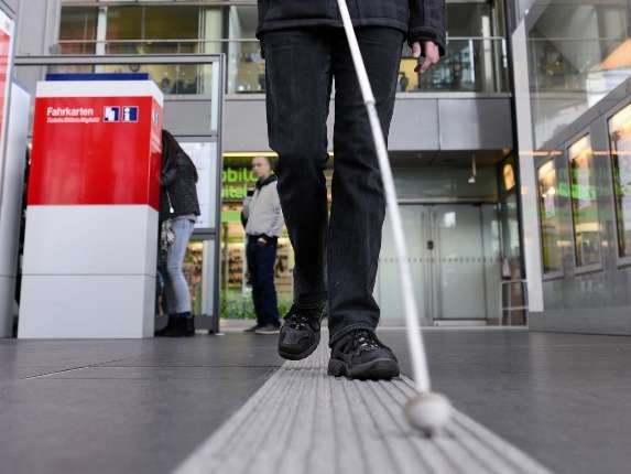 Man with sunglasses a walking stick for the blind on white tactile floor