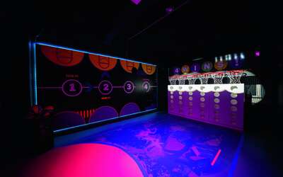 eine buntbeleuchtete Halle mit sechs Basketballkörben nebeneinander.