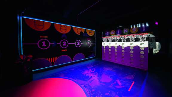 eine buntbeleuchtete Halle mit sechs Basketballkörben nebeneinander.