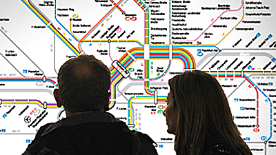 Paar steht vor einem Liniennetzplan und schaut ihn sich an