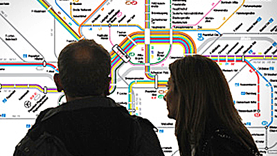 Ein Paar steht vor einem Liniennetzplan und schaut ihn sich an.