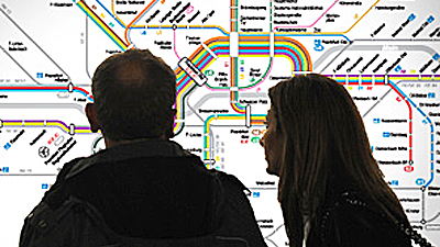 Ein Paar steht vor einem Liniennetzplan und schaut ihn sich an.