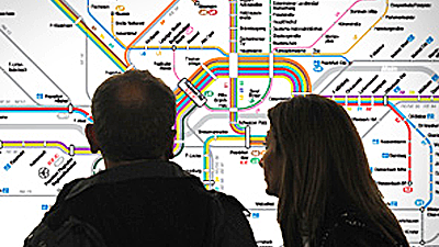 Paar steht vor einem Liniennetzplan und schaut ihn sich an