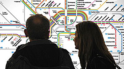 Ein Paar steht vor einem Liniennetzplan und schaut ihn sich an.