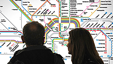 Ein Paar steht vor einem Liniennetzplan und schaut ihn sich an.