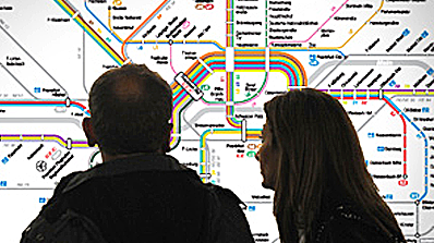 Ein Paar steht vor einem Liniennetzplan und schaut ihn sich an.