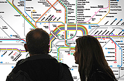 Ein Paar steht vor einem Liniennetzplan und schaut ihn sich an.