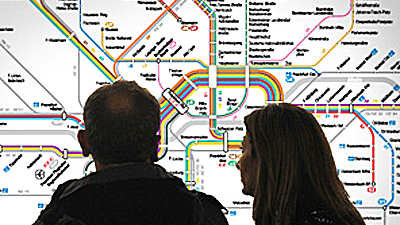 Ein Paar steht vor einem Liniennetzplan und schaut ihn sich an.