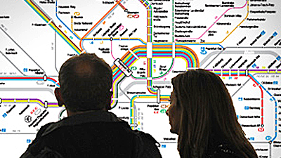 Ein Paar steht vor einem Liniennetzplan und schaut ihn sich an.