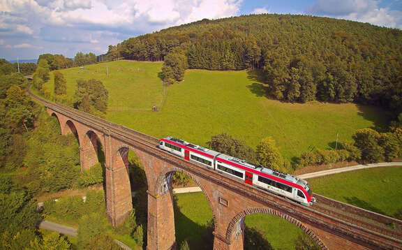 Ein Zug fährt über ein Viadukt, Hintergrund grüne Landschaft