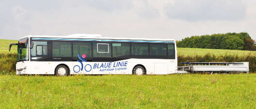Blue line bus with bike trailer in the landscape